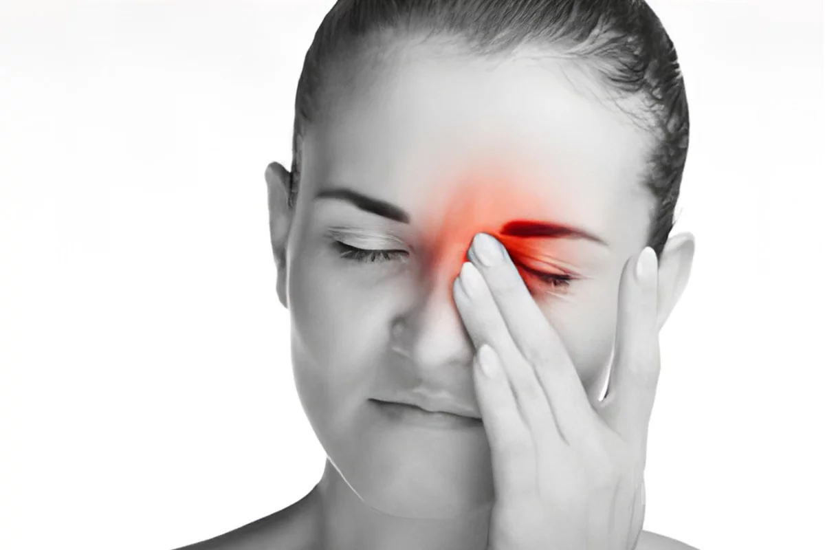 Black and white image of woman experiencing a migraine. There is red coloring around her left eye to indicate retinal migraine.